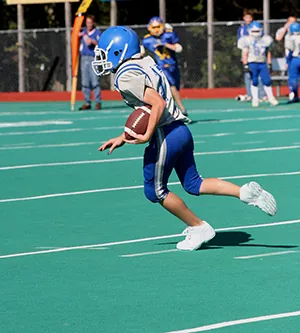 Young football player running with a ball on the field