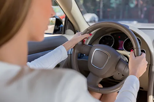 Driver behind the wheel of a car with one arm in a shoulder sling
