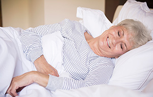 Older woman sleeping comfortably on her side, propped up on soft pillows