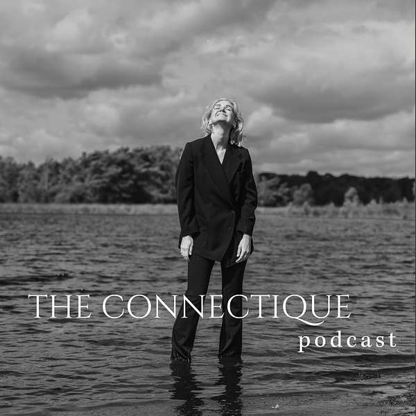 Black and white photo of a smiling woman in a dark suit standing knee-deep in water with a cloudy sky and trees in the background, overlaid with text 'THE CONNECTIQUE podcast'.