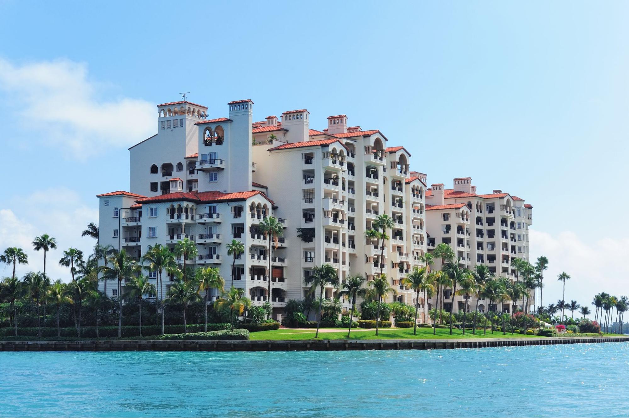 A modern apartment building near a lake with trees around it.
