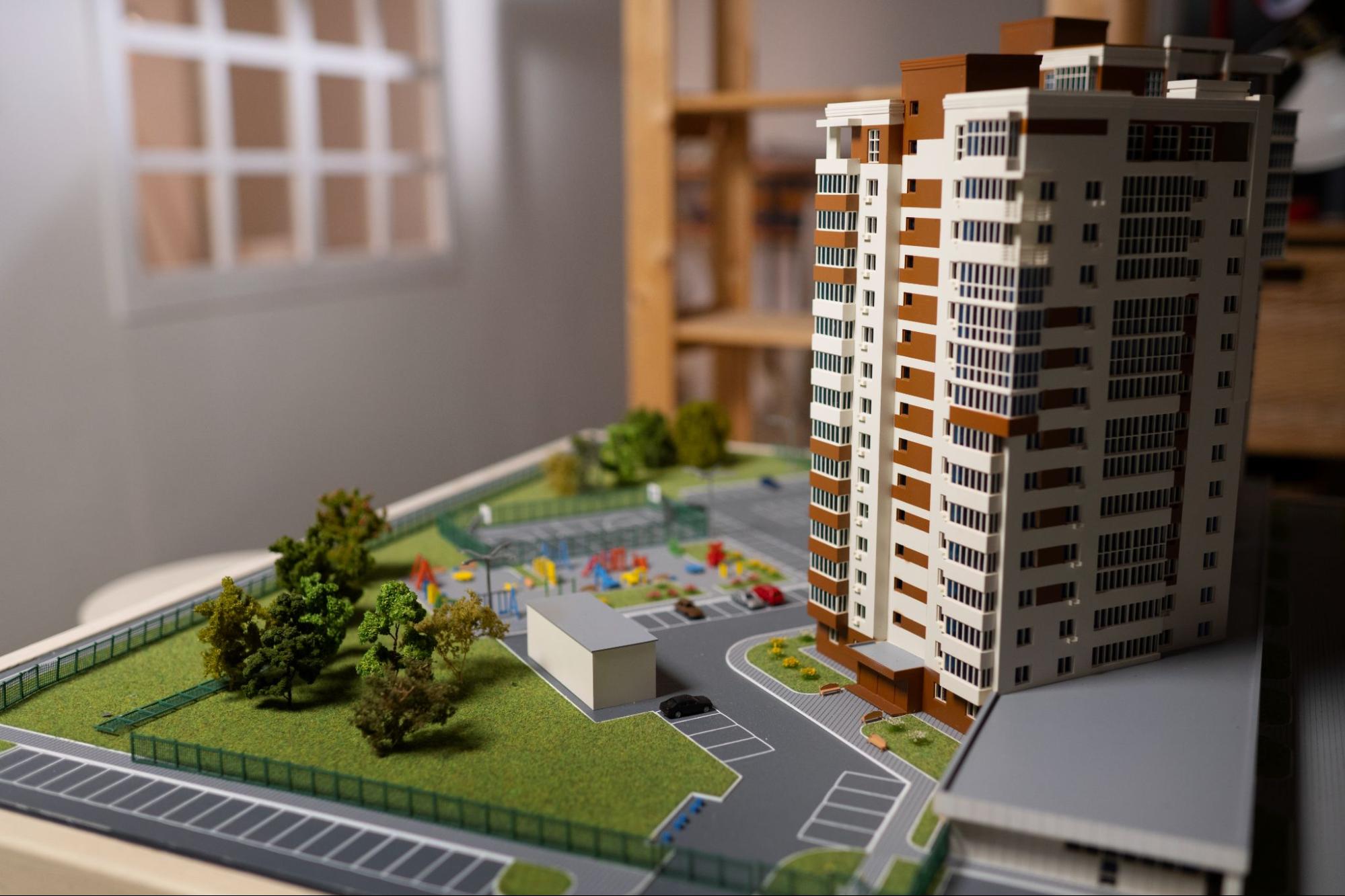 A model of an apartment building with a ground and parking lot.