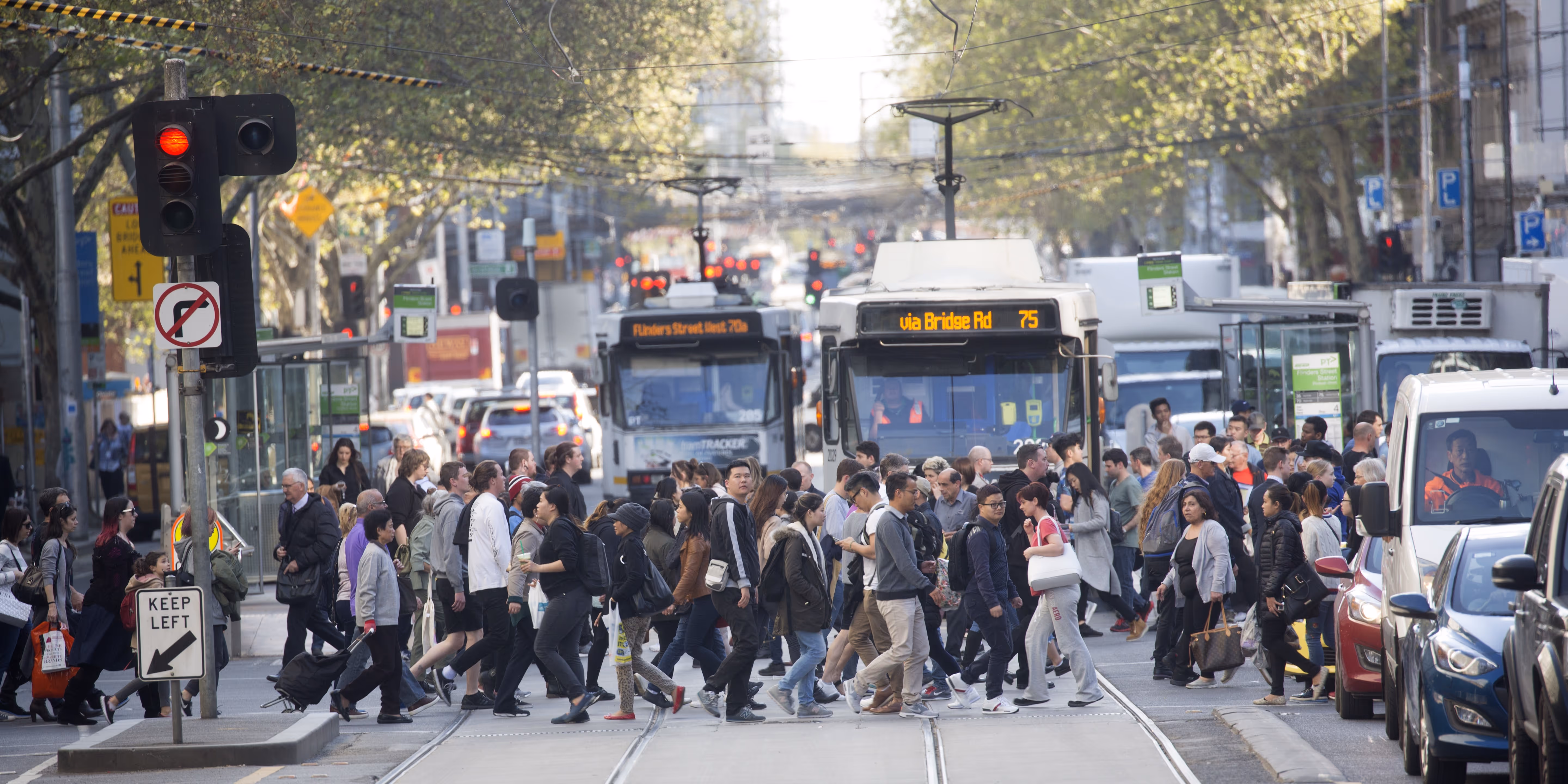 A busy city pedestrian crossing with heavy traffic waiting