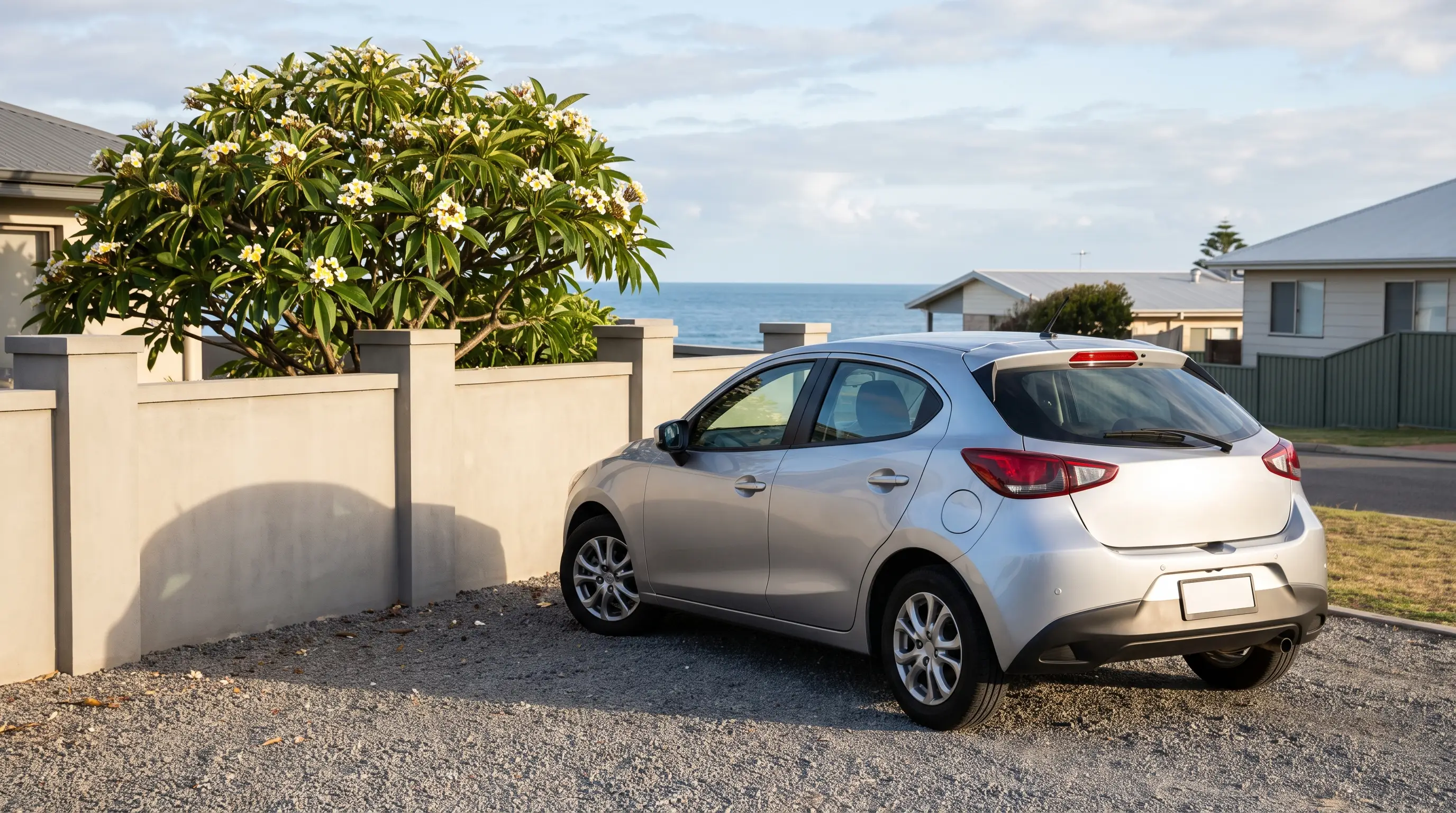 Silver hatchback parked in a quiet coastal suburban driveway in morning light