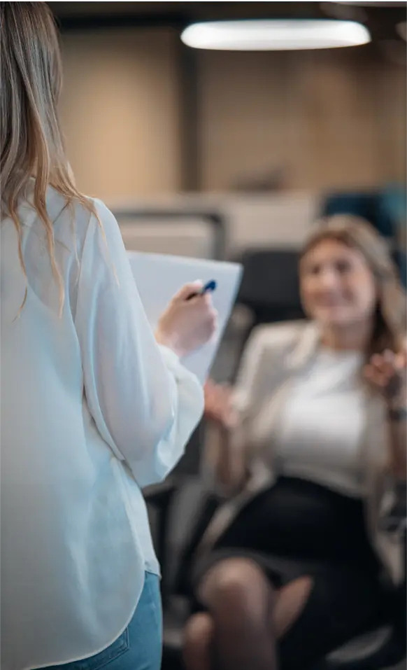 A woman standing next to a woman holding a clipboard.