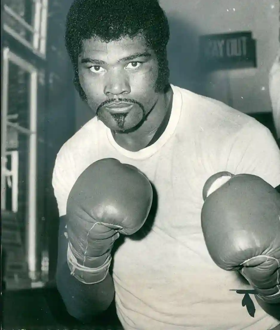 Mac Foster posing in a light shirt and boxing gloves