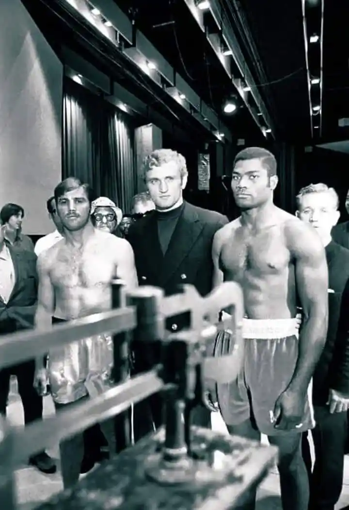 Mac Foster standing beside a weigh-in scale with other men