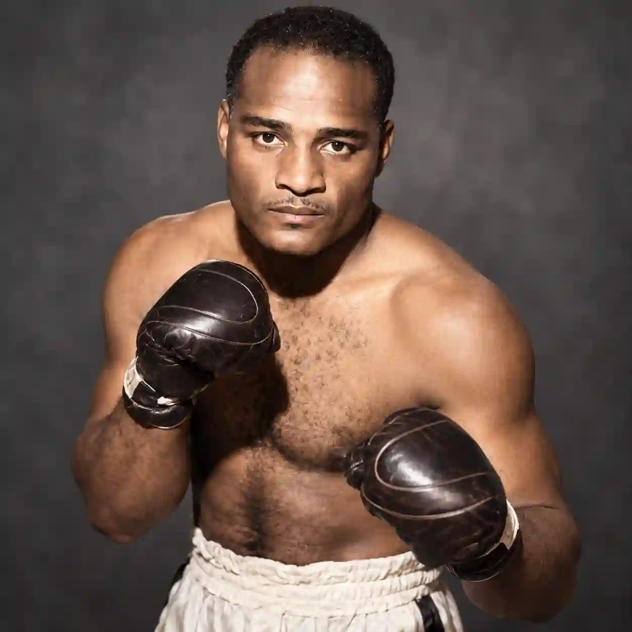 Zora Folley posing with dark boxing gloves and white trunks