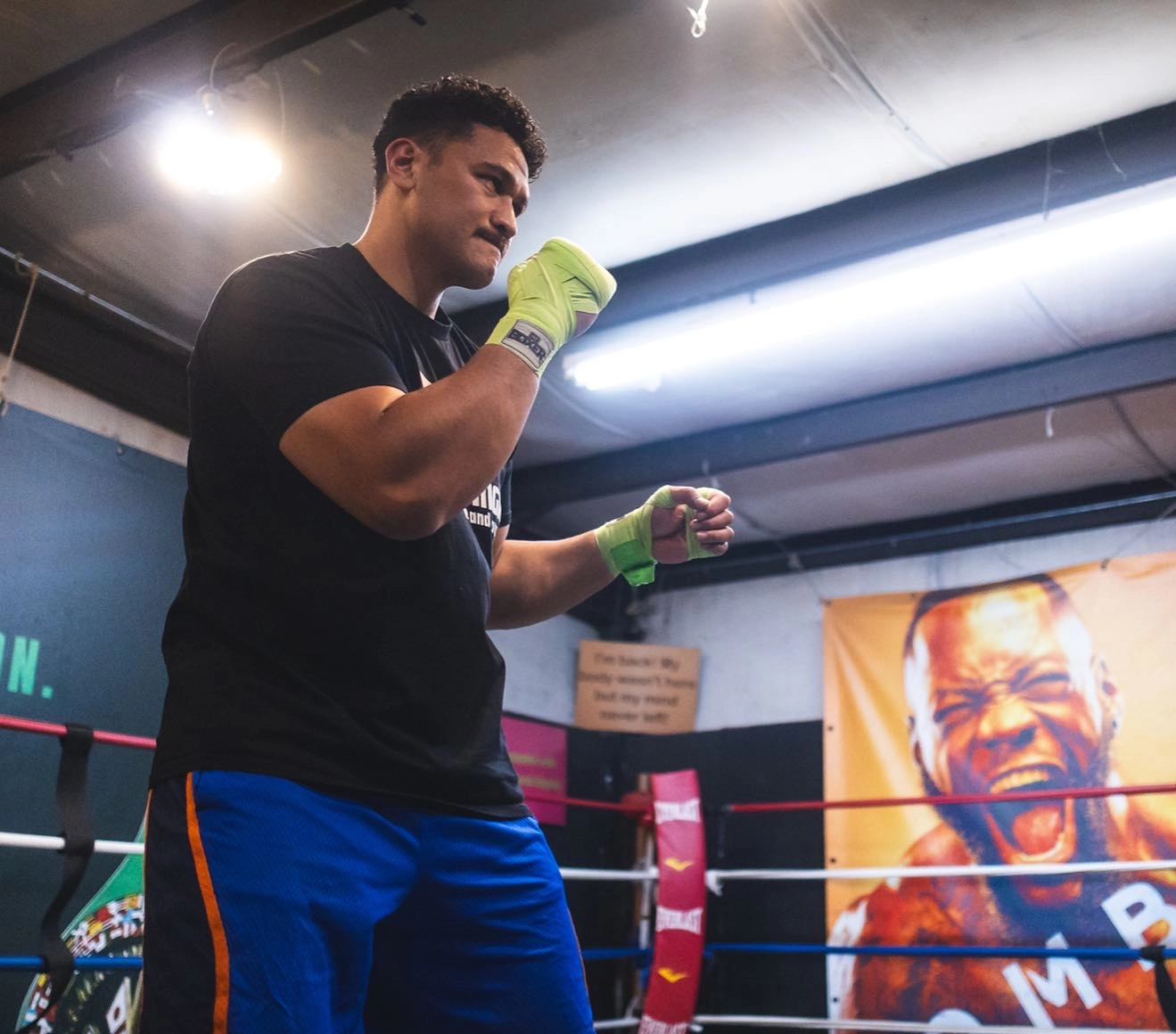 Junior Fa training in a boxing ring with bright green hand wraps.