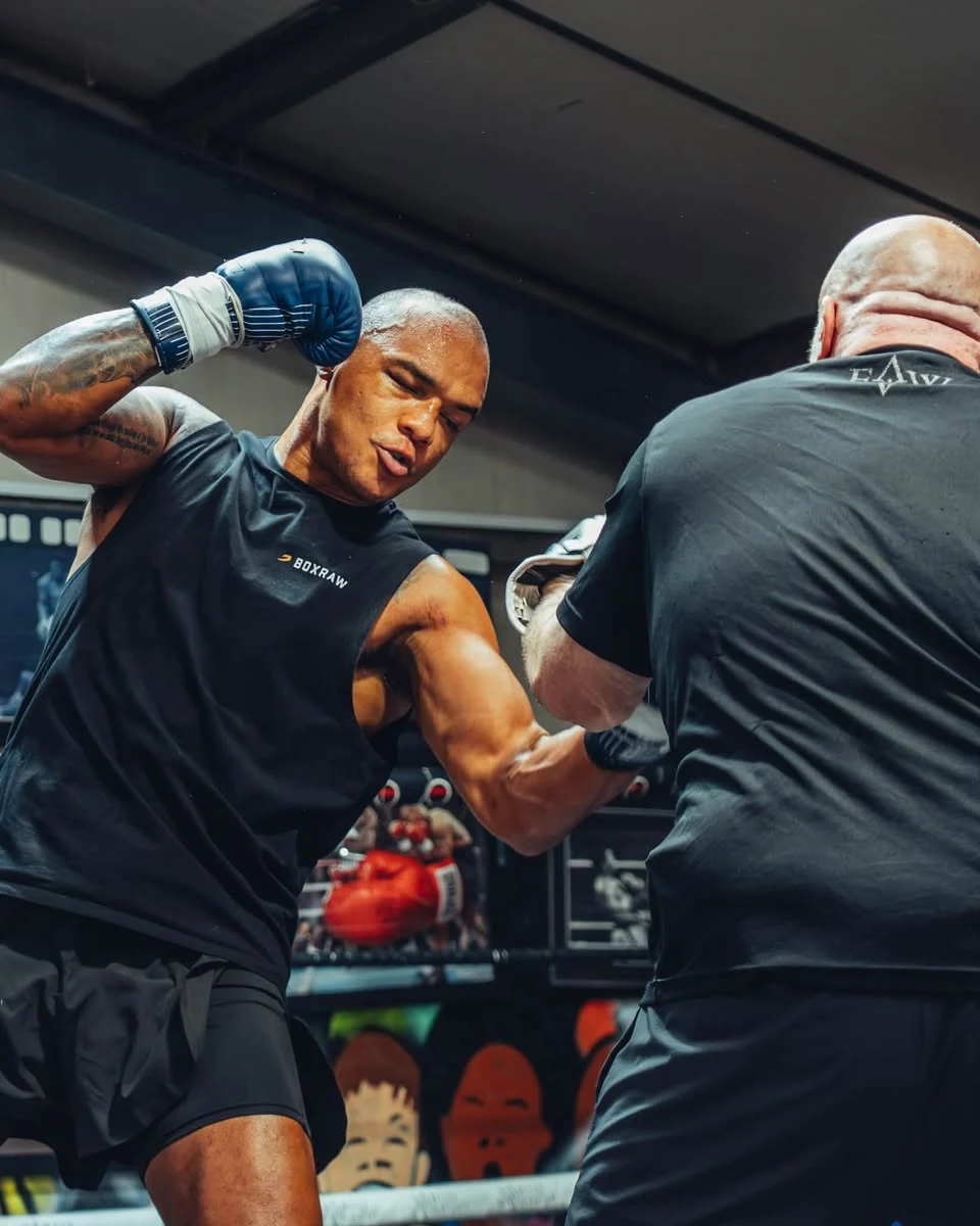 Fabio Wardley wearing blue gloves during a pad session in the gym.