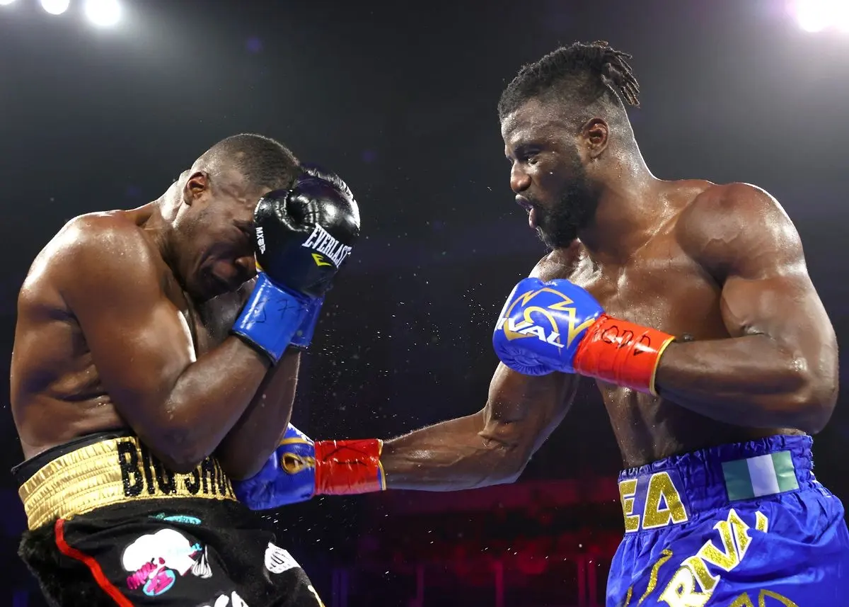 Efe Ajagba in blue trunks extending a glove toward an opponent covering his head.