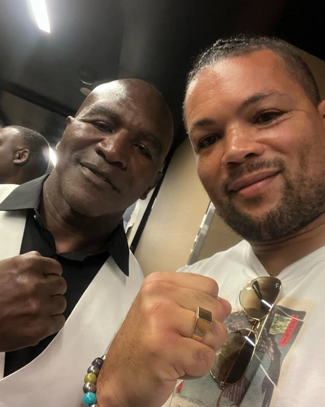Evander Holyfield and Joe Joyce posing close to the camera with their fists raised.
