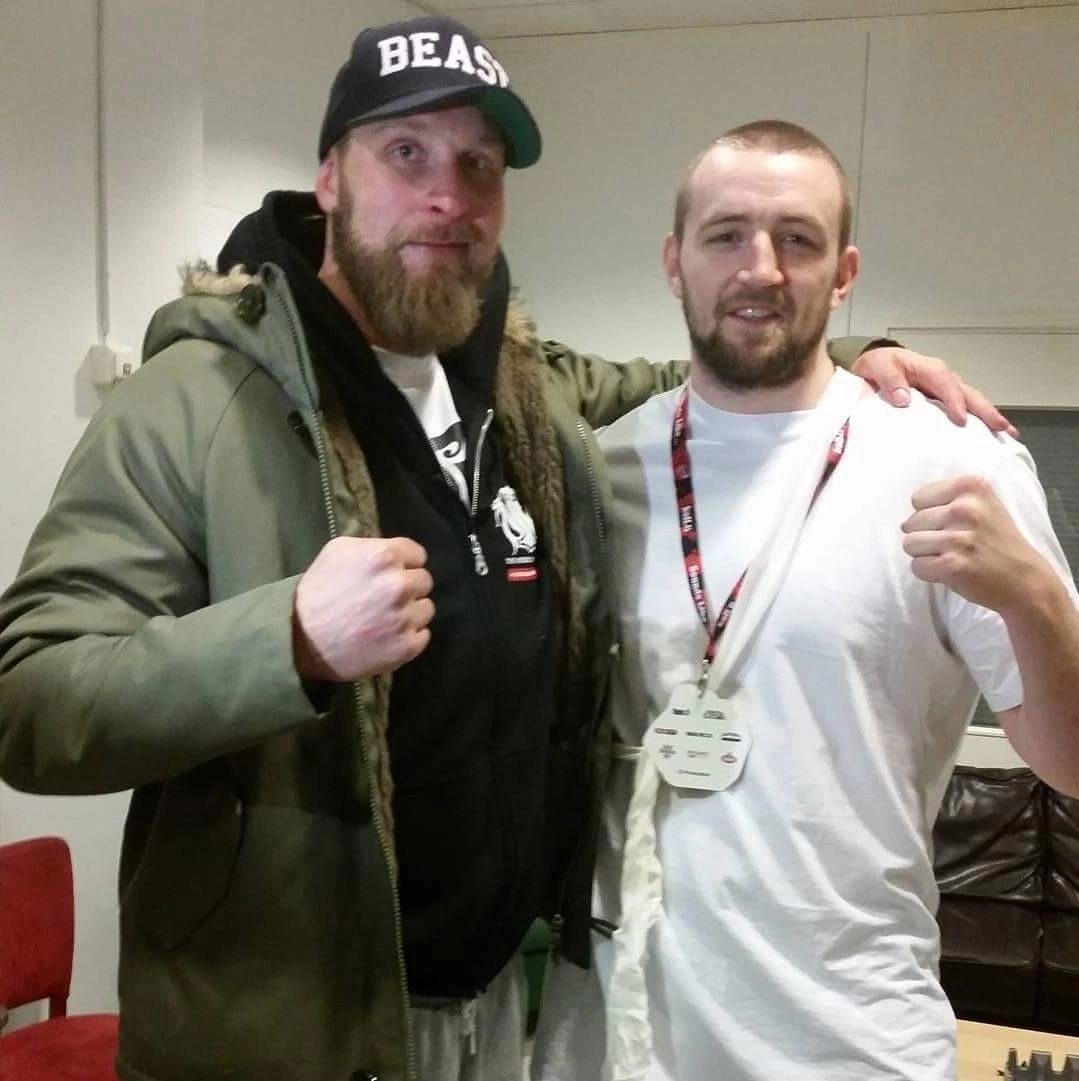 Robert Helenius in a Beast cap and Kolbeinn Kristinsson in a white shirt posing together with fists raised.
