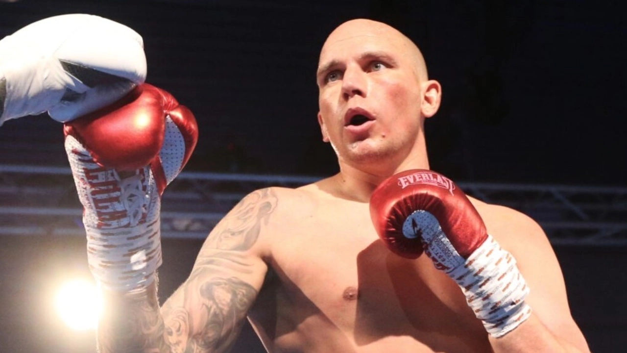 Kem Ljungquist in the boxing ring with red gloves and a white towel draped over his raised glove.