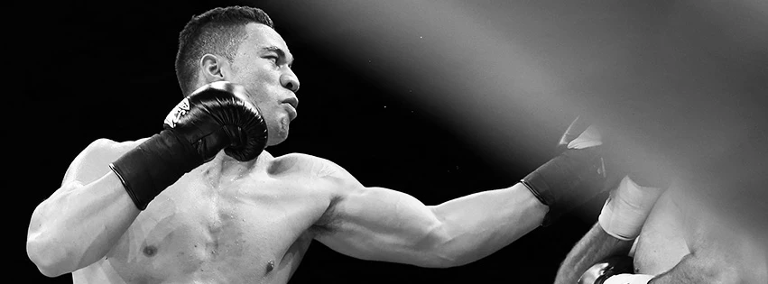 Black-and-white image of Joseph Parker extending a black-gloved punch toward a partially cropped opponent.