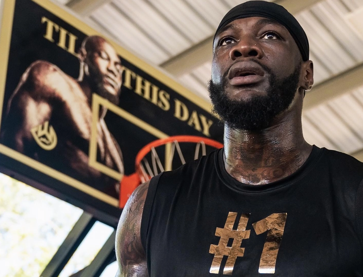 Deontay Wilder pauses during training in front of a Wilder poster.