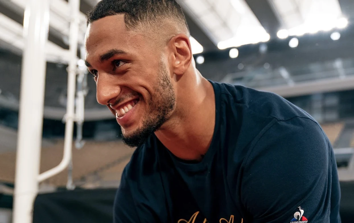 Tony Yoka smiles while seated in a boxing gym.