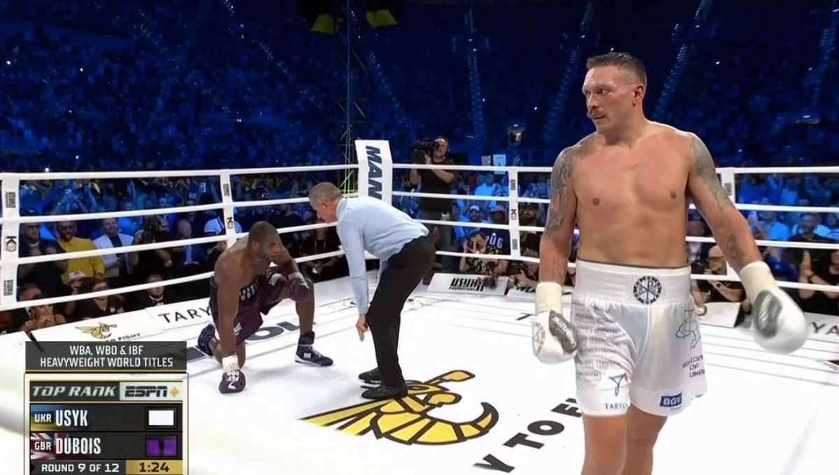 Oleksandr Usyk walks away as the referee counts over Daniel Dubois kneeling on the canvas in round nine.