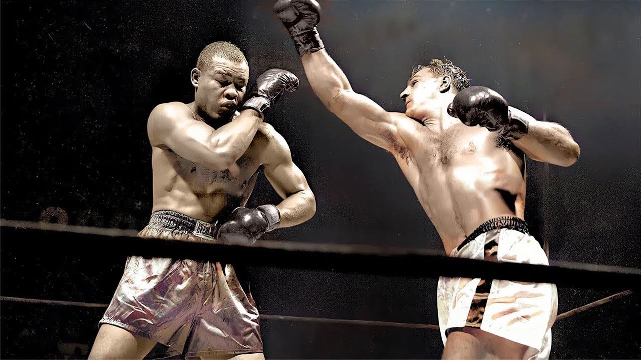 Colourised video thumbnail showing Rocky Marciano throwing a punch as Joe Louis raises his guard.