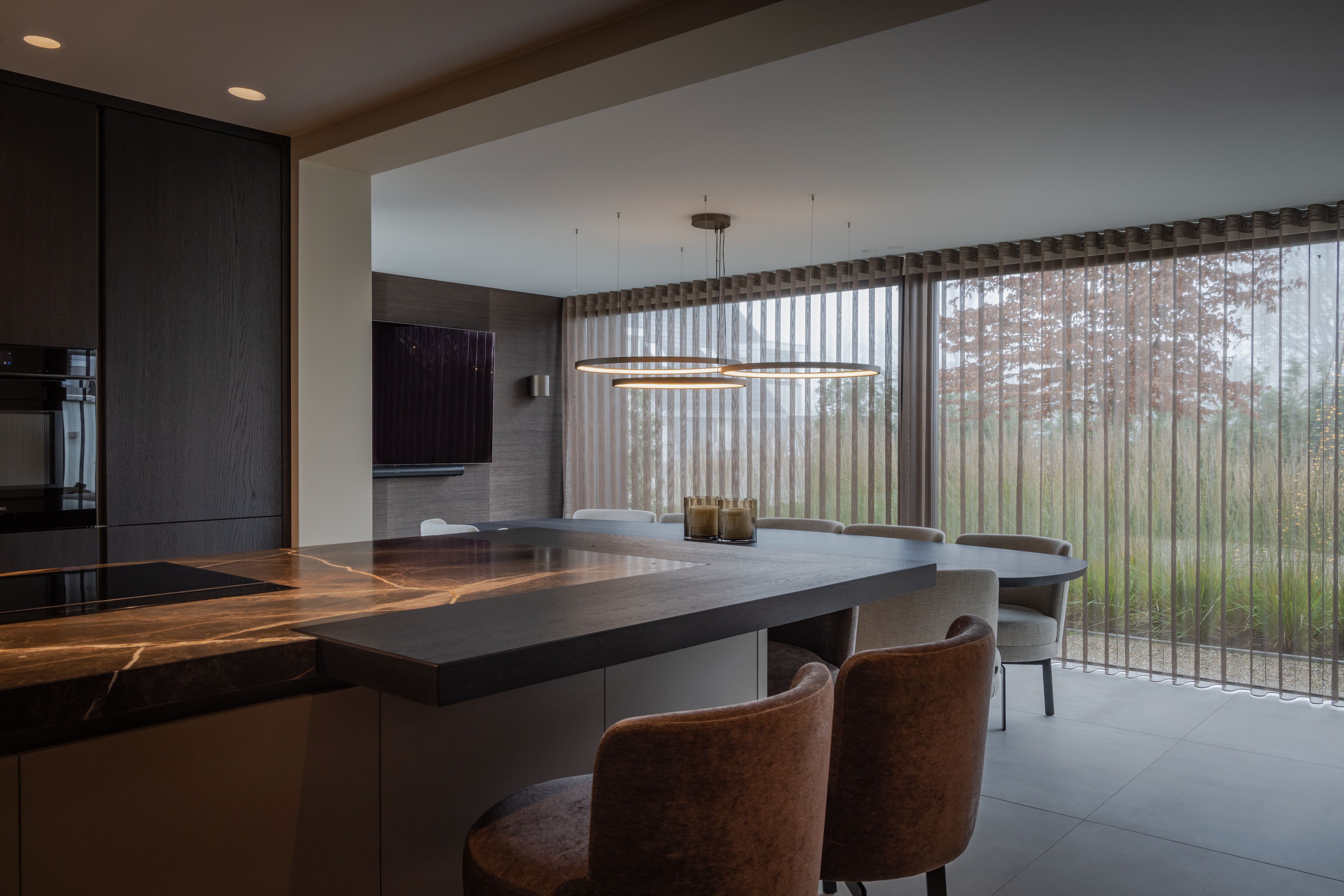 Open keuken en eetkamer met maatwerk keukeneiland, barzit en royale raampartij