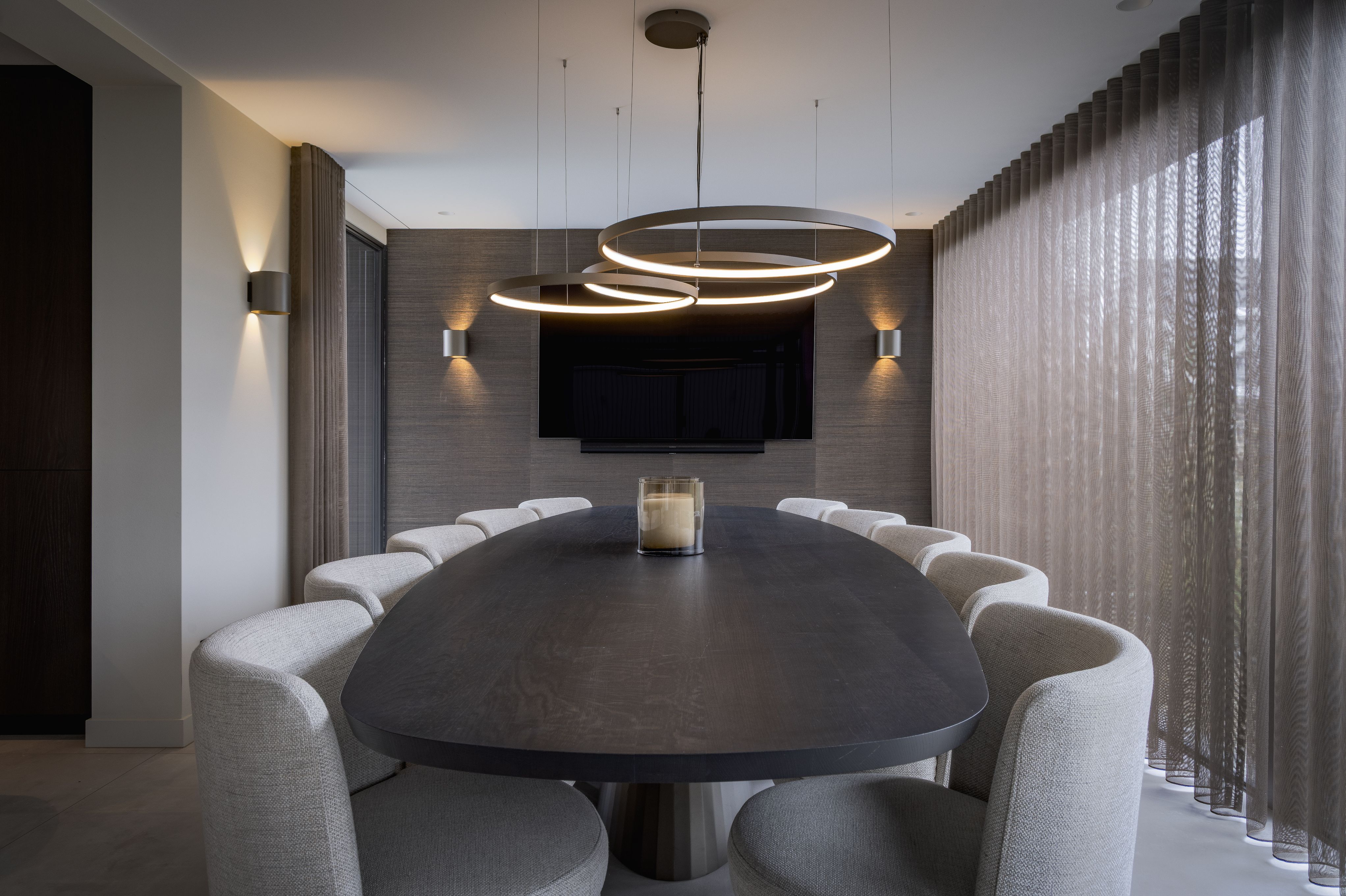 Luxe eetkamer met royale eettafel, gestoffeerde eetkamerstoelen en ringvormige verlichting
