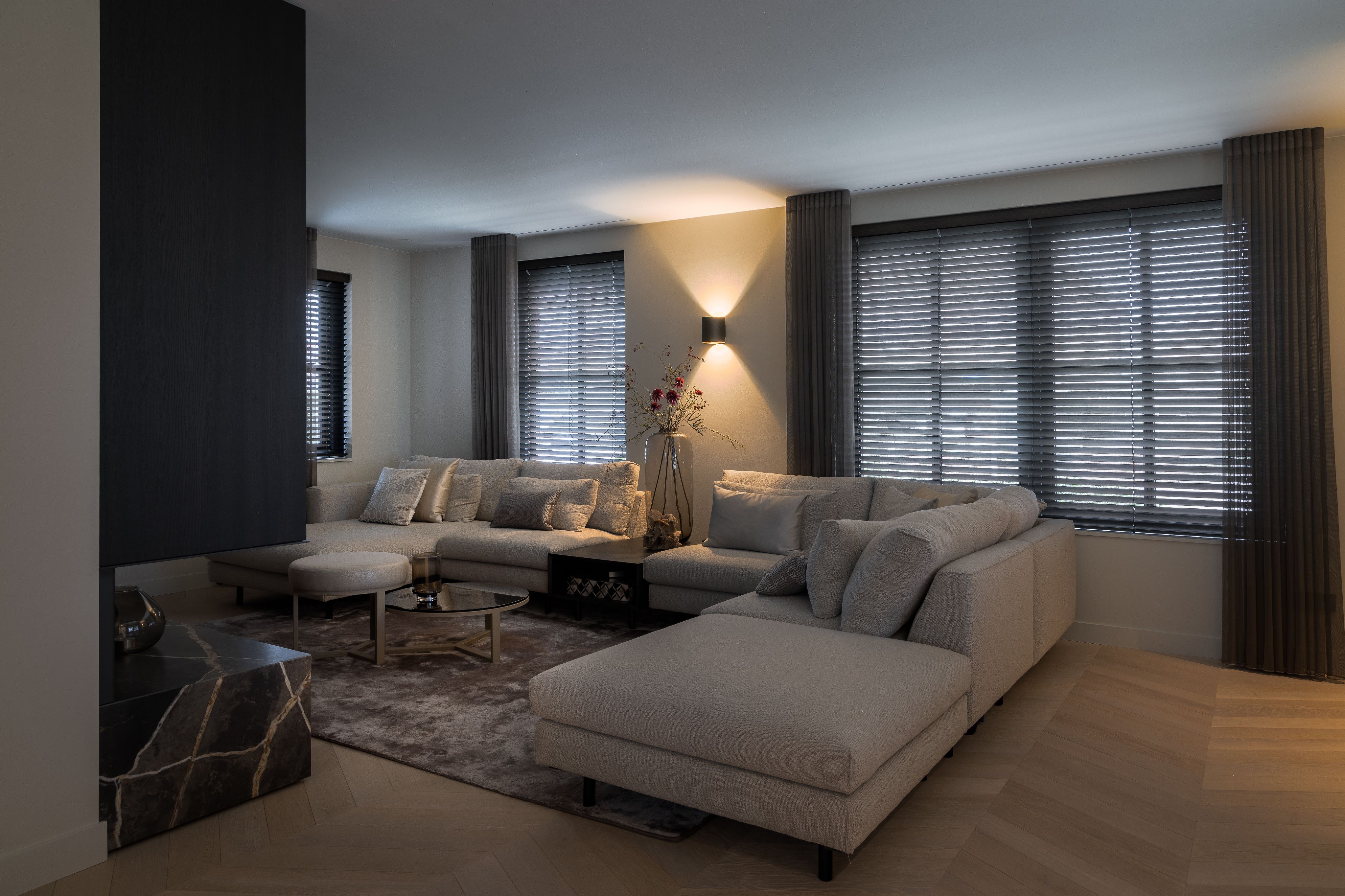 Luxe woonkamer met royale hoekbank, maatwerk tv-wand en warme sfeerverlichting