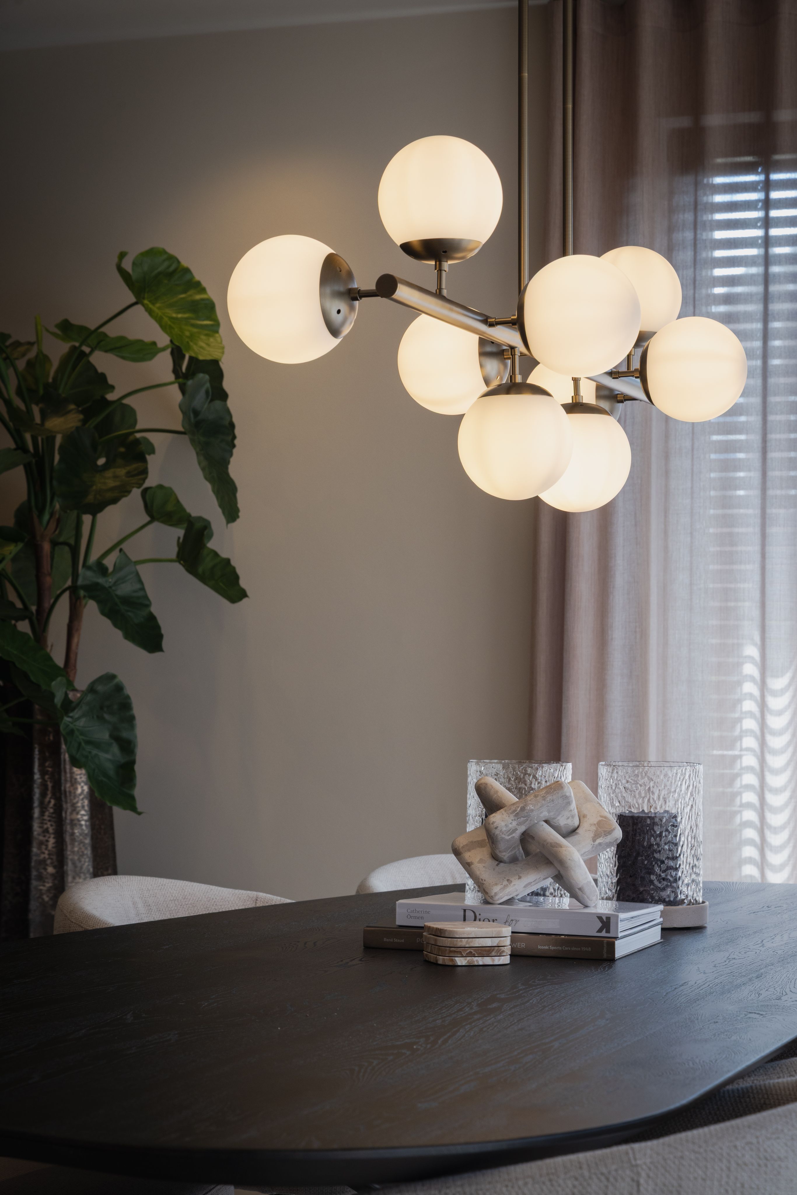 Donkere eettafel met sculpturale hanglamp en lichte eetkamerstoelen