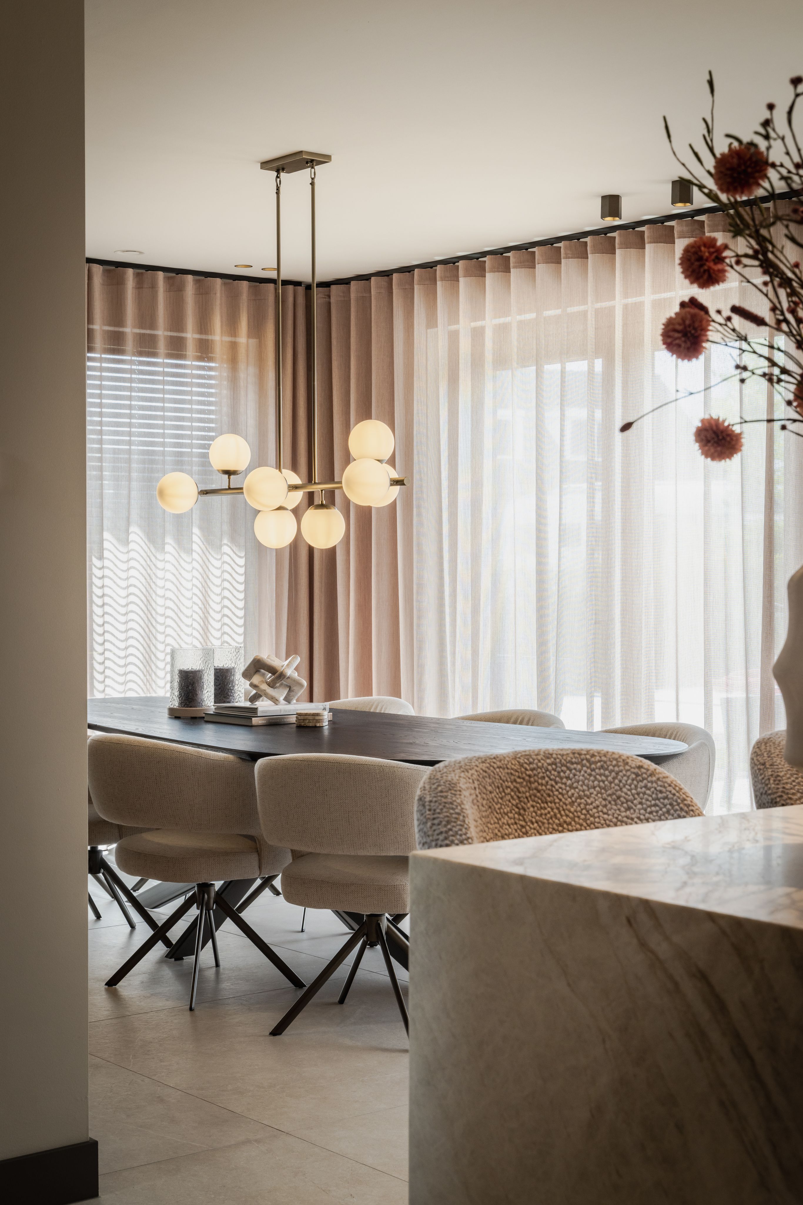 Eetkamer met donkere eettafel, lichte stoelen en natuurstenen kookeiland