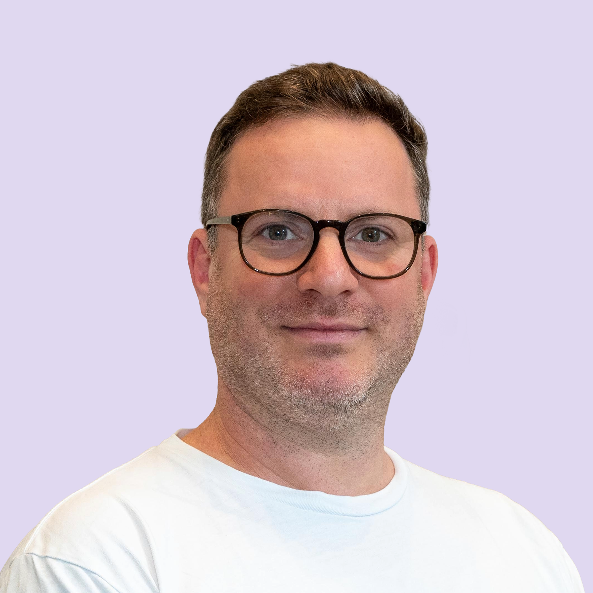 Portrait of David Kipnis with short brown hair and glasses wearing a white shirt against a light purple background.