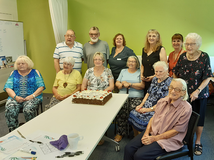group of ladies and gentleman around a cake