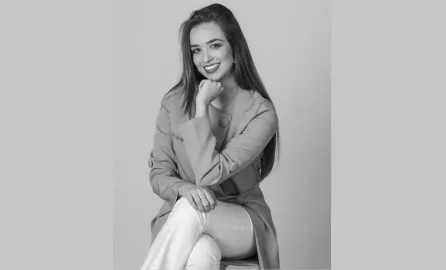 Жена в сиво се усмихва на бял фон