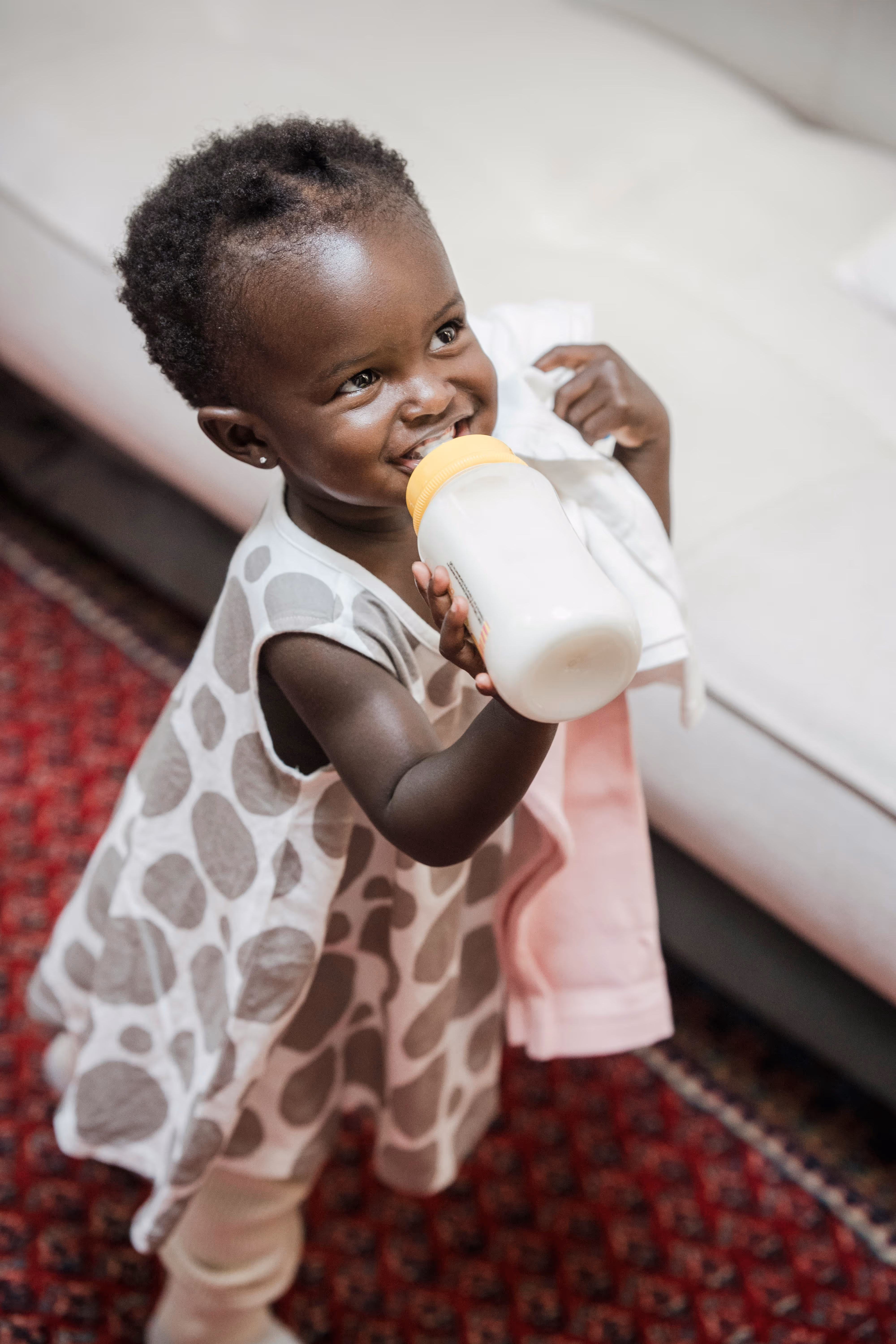 A young girl holds a bottle filled with infant formula