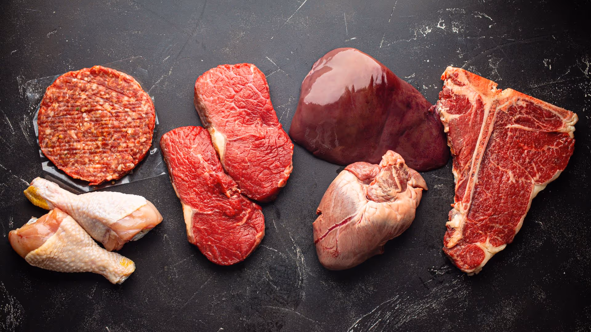 Different types of raw meat are laid out on a cooking surface.