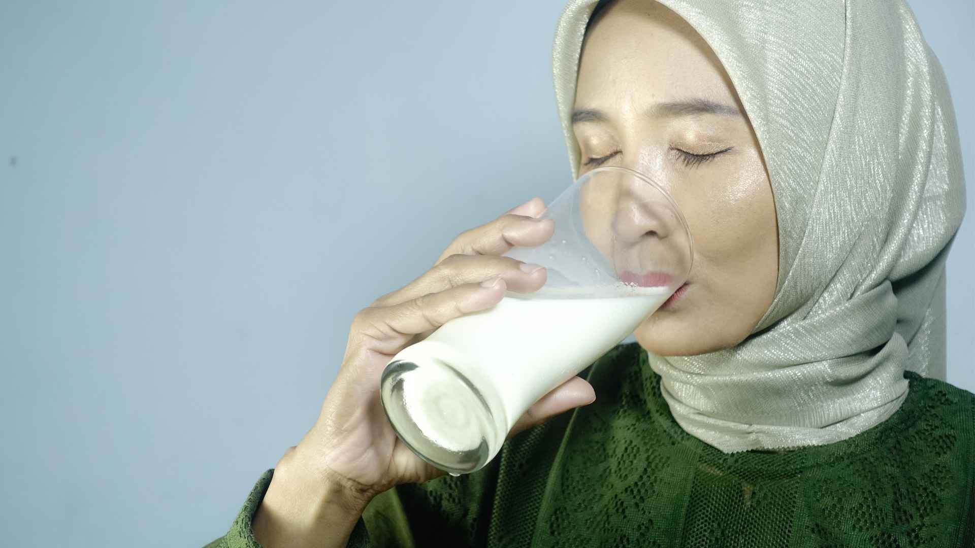 A woman drinks a glass of milk
