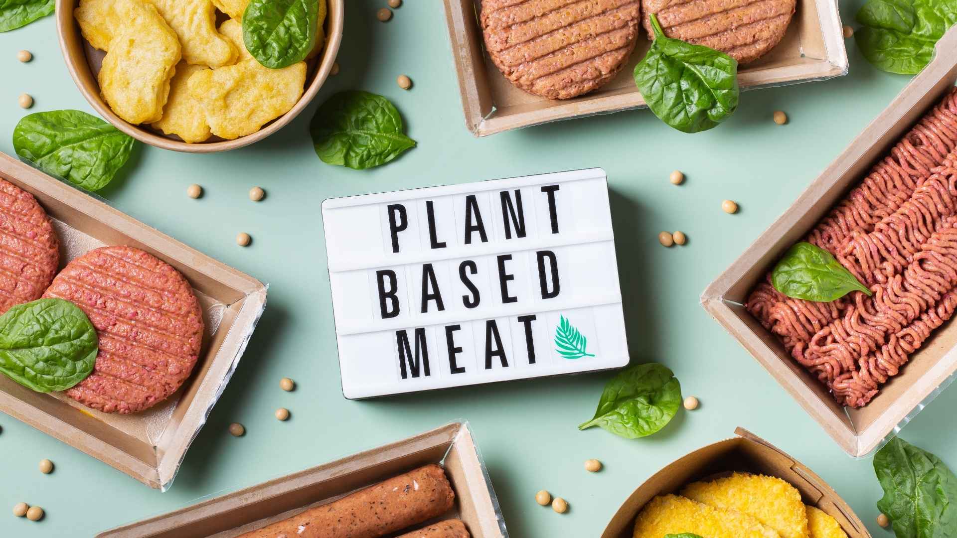 Various types of plant-based meat surround a sign that reads 'plant based meat'