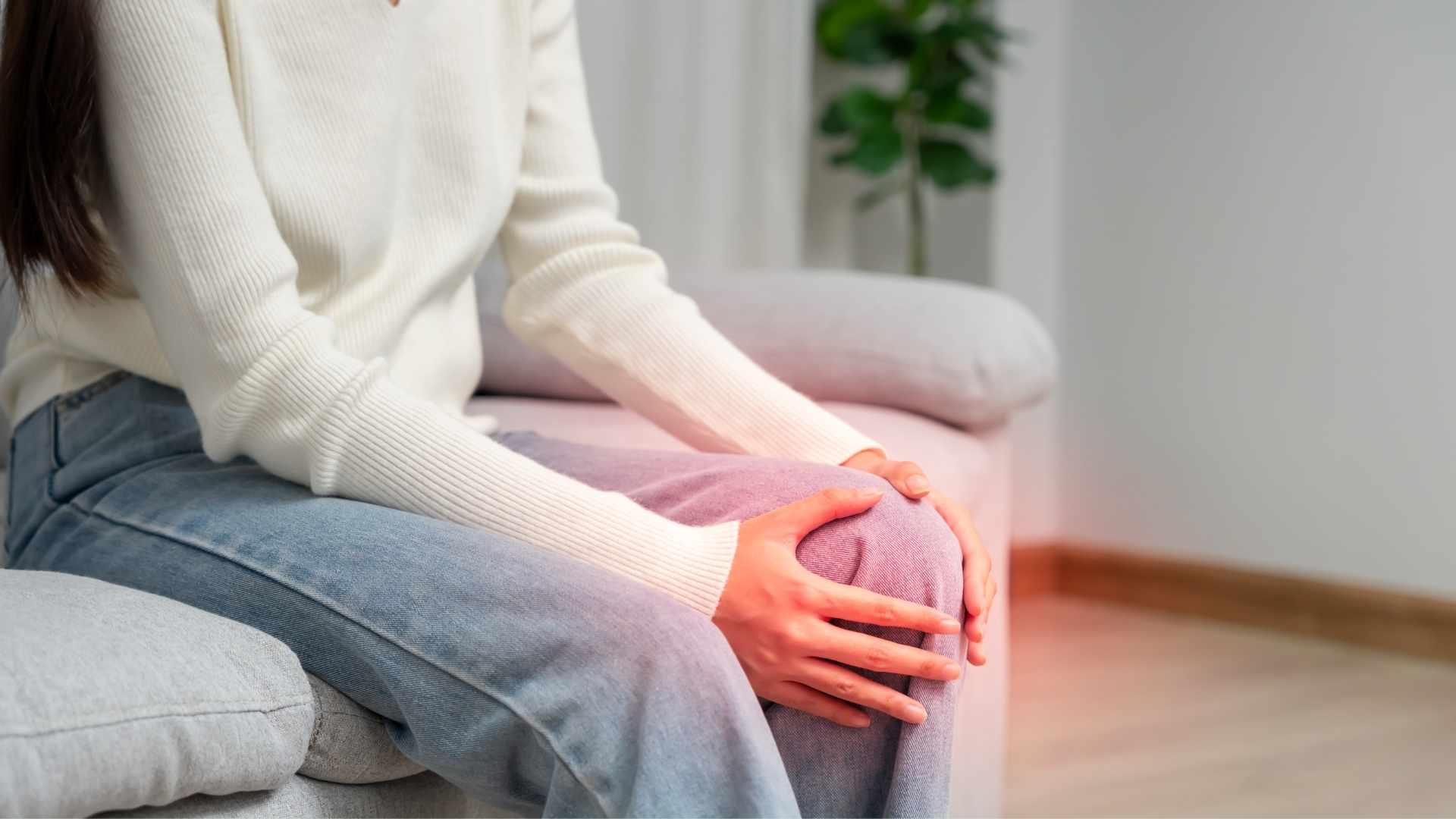 A woman holds her knee, clearly in pain due to inflammation
