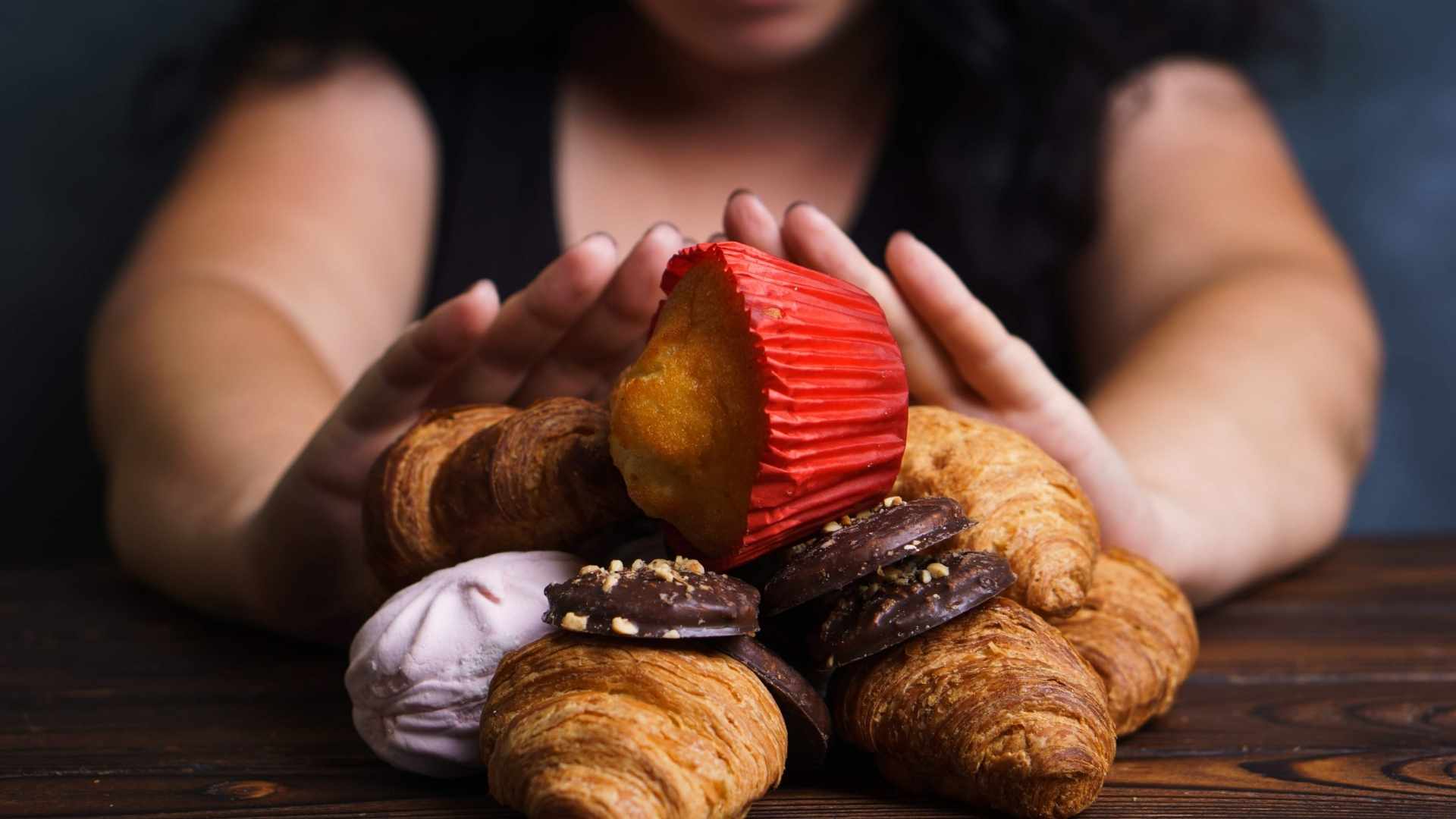 A person holds their hands up to block an array of desserts