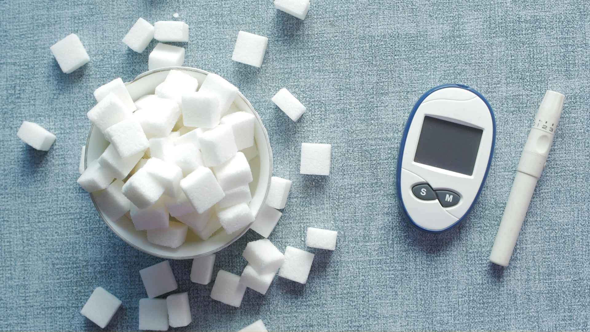 A bowl of sugar is next to a glucose monitor