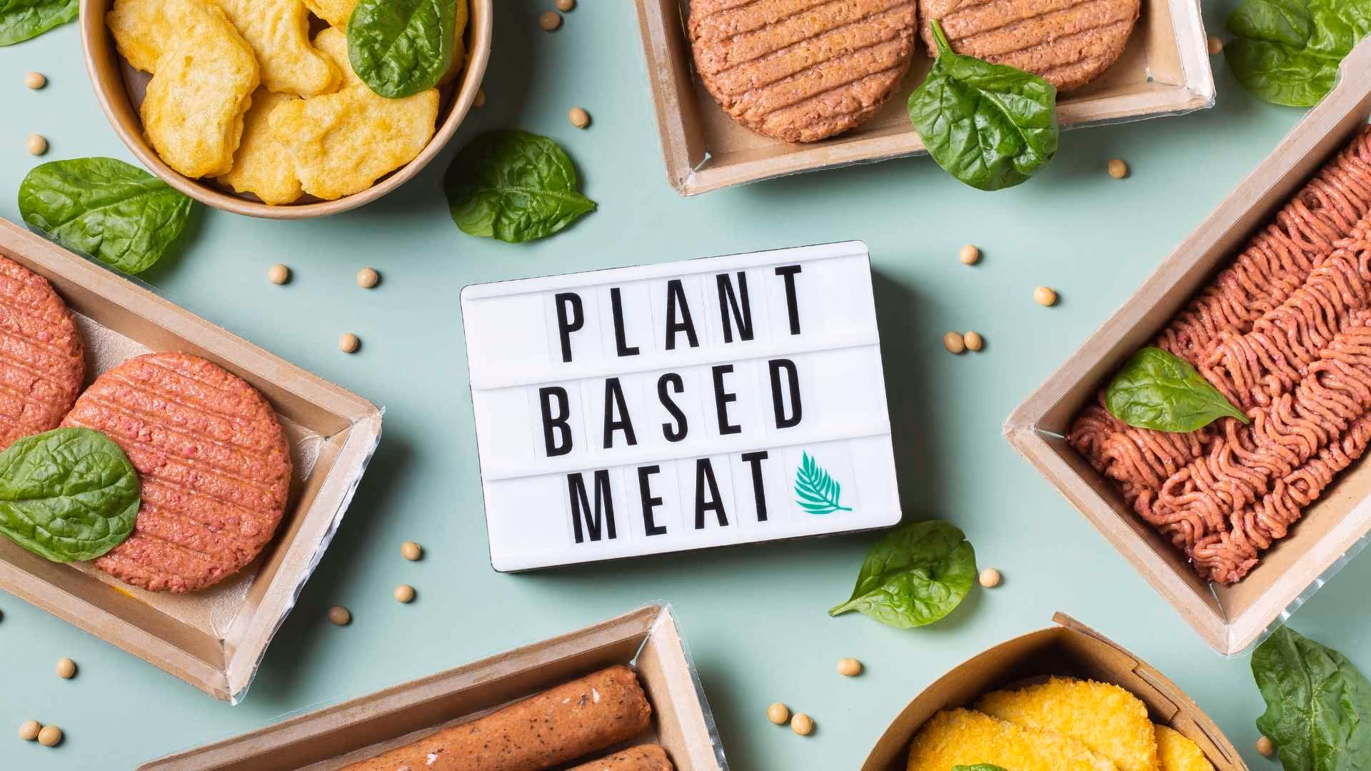 Various types of plant-based meat surround a sign that reads 'plant based meat'