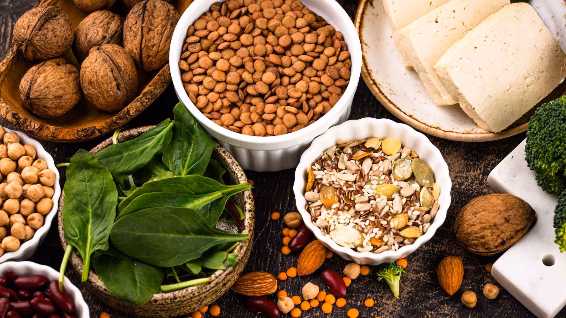 A range of whole plant proteins, such as nuts, legumes, and tofu, are on a platter