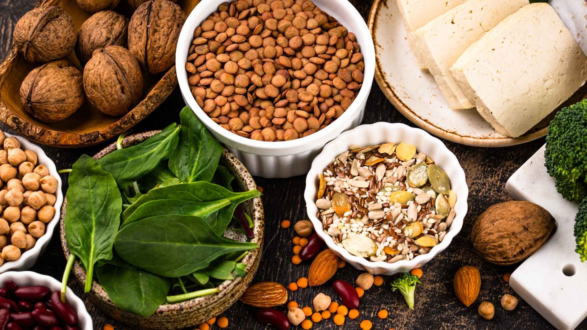 A range of whole plant proteins, such as nuts, legumes, and tofu, are on a platter