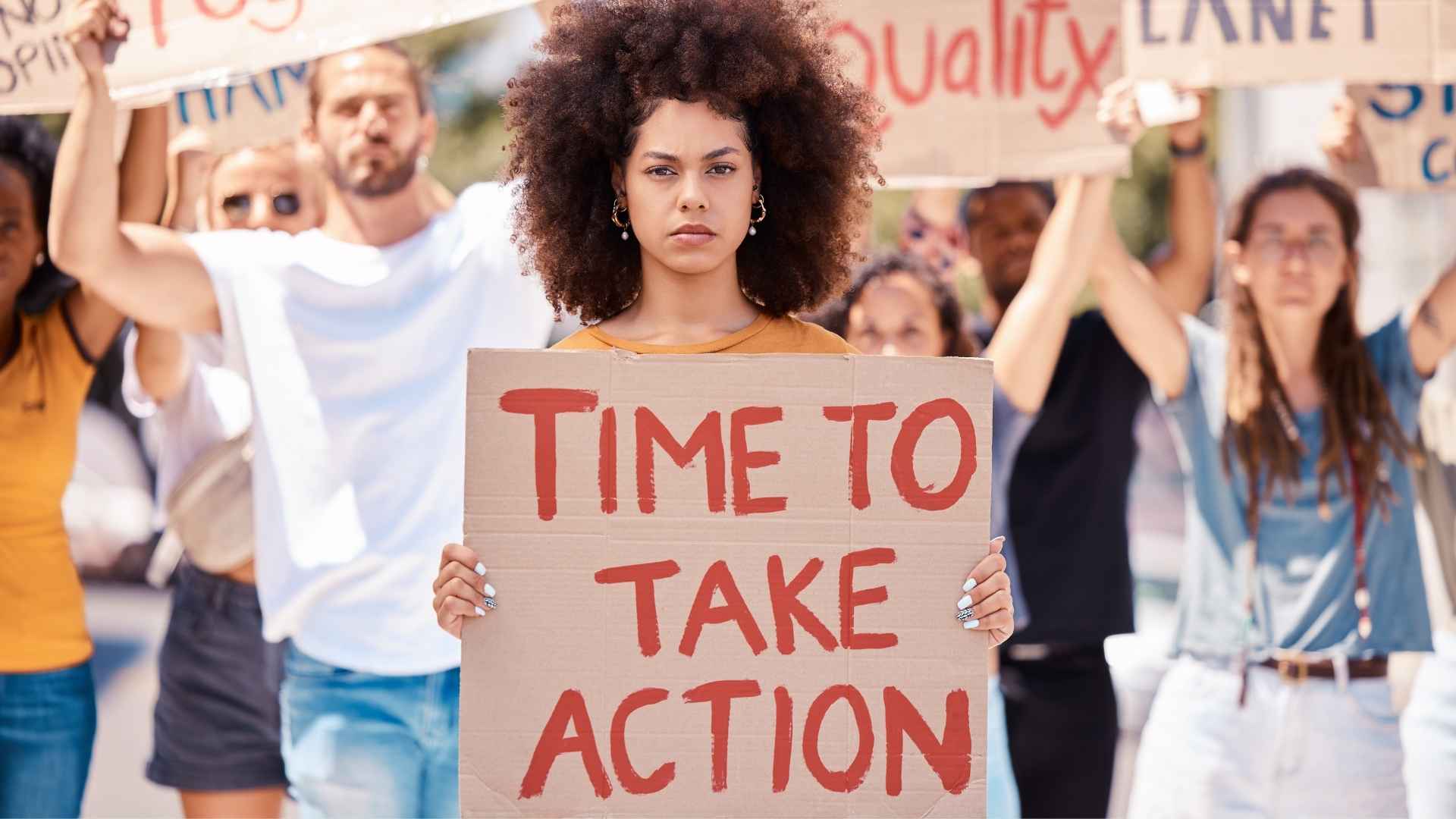 A protesting woman holds up a sign that reads 'Time to take action'