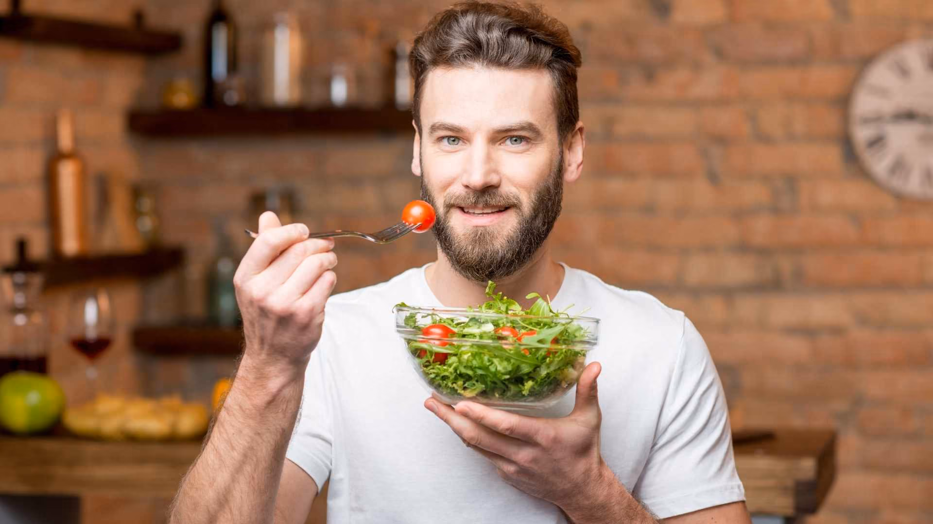 A man holds a bowl of salad