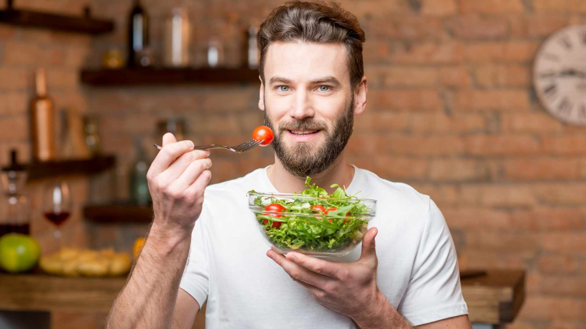 A man holds a bowl of salad