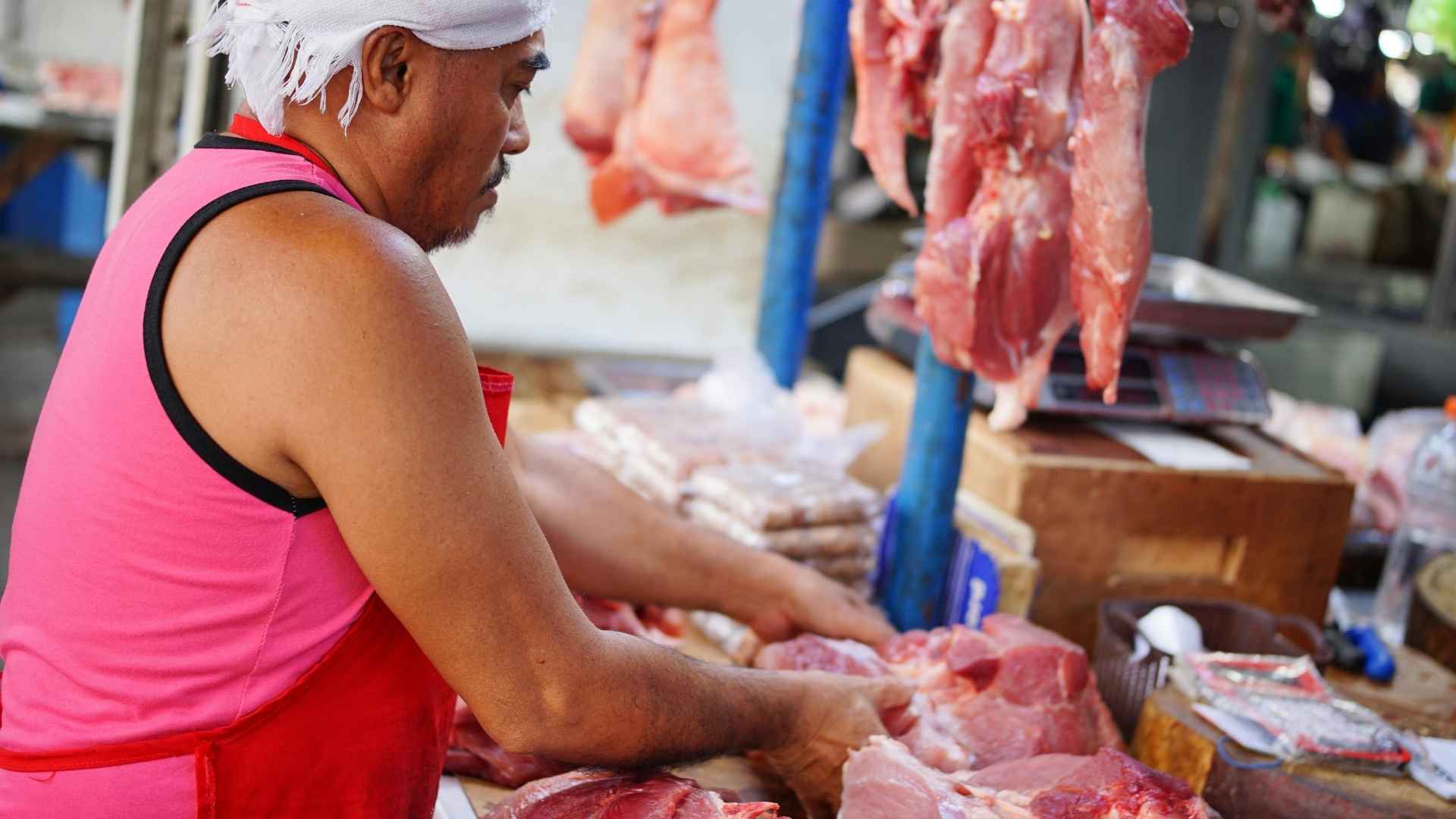 A person chops meat in a meat market