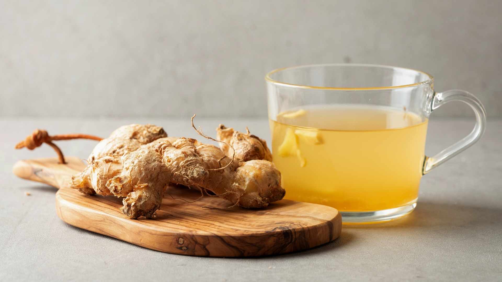 A bulb of root ginger is next to a mug of ginger tea