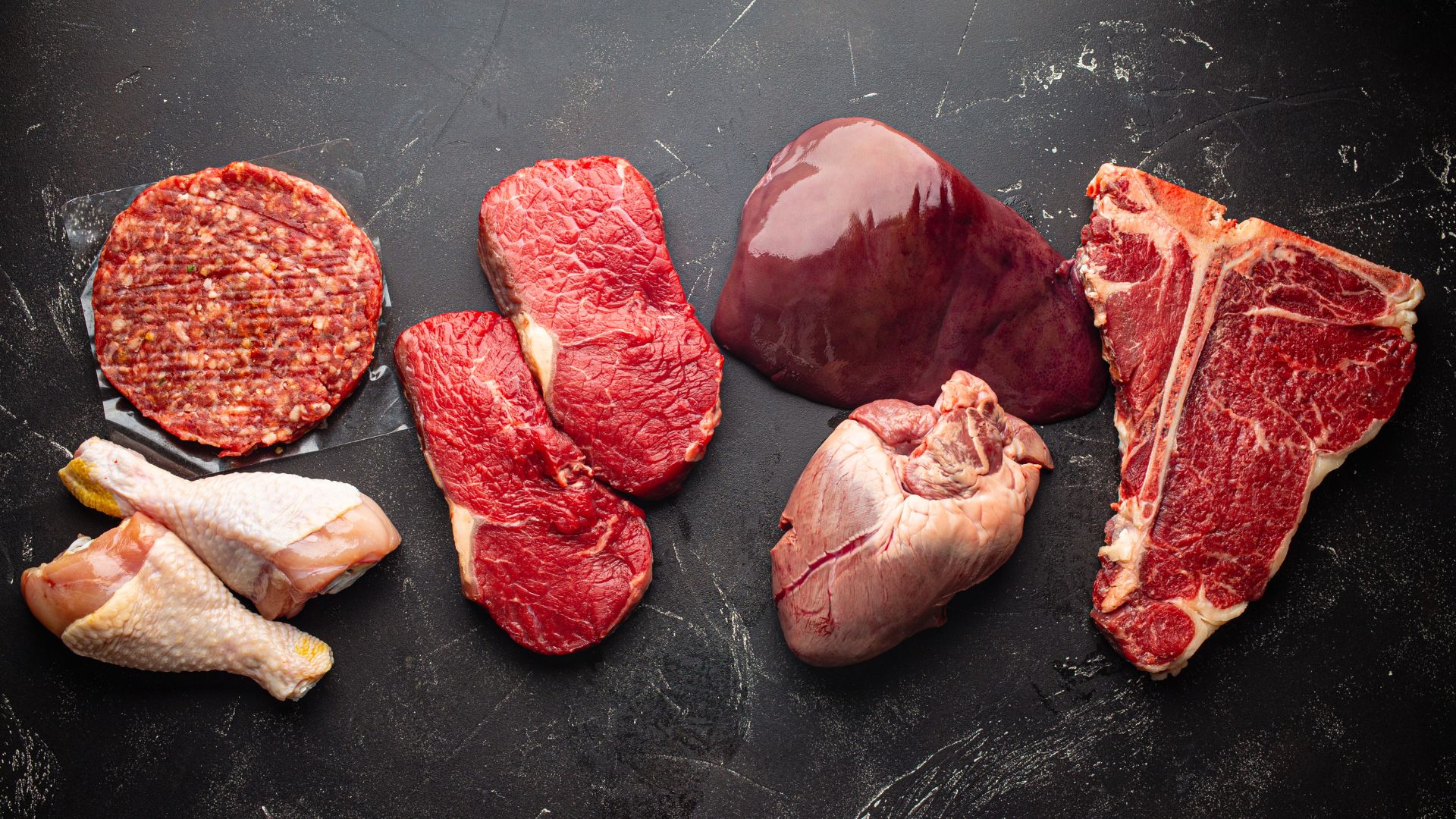 Different types of raw meat are laid out on a cooking surface.
