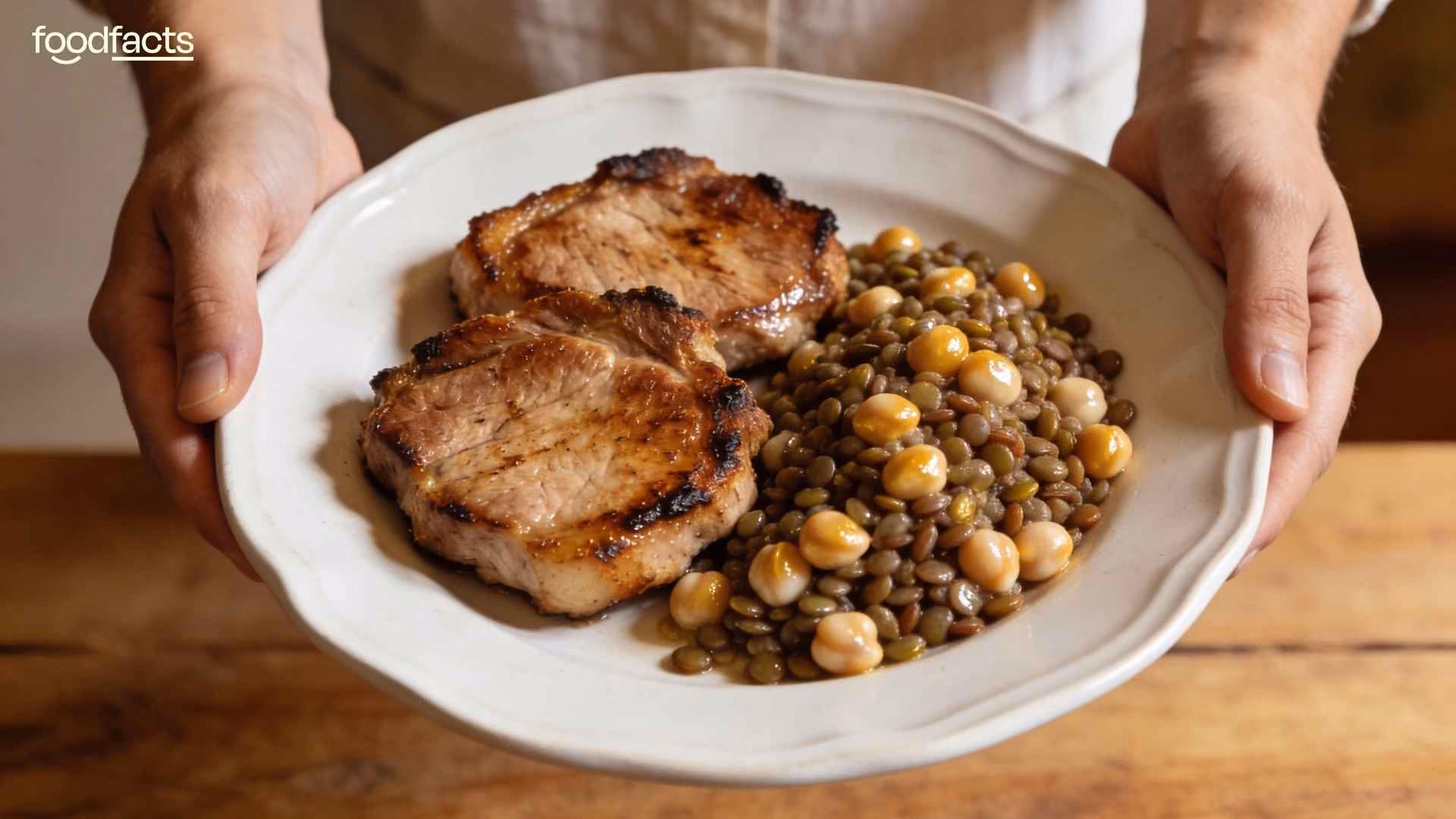 A person holds a plate of porkchops and lentils