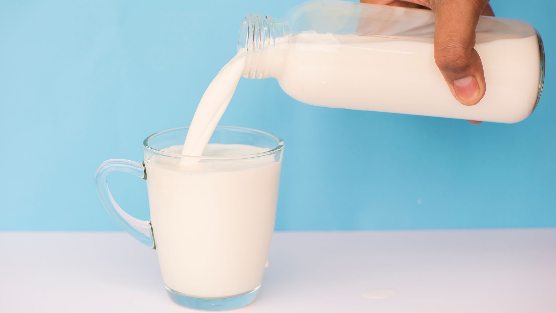 A person pours a glass of milk