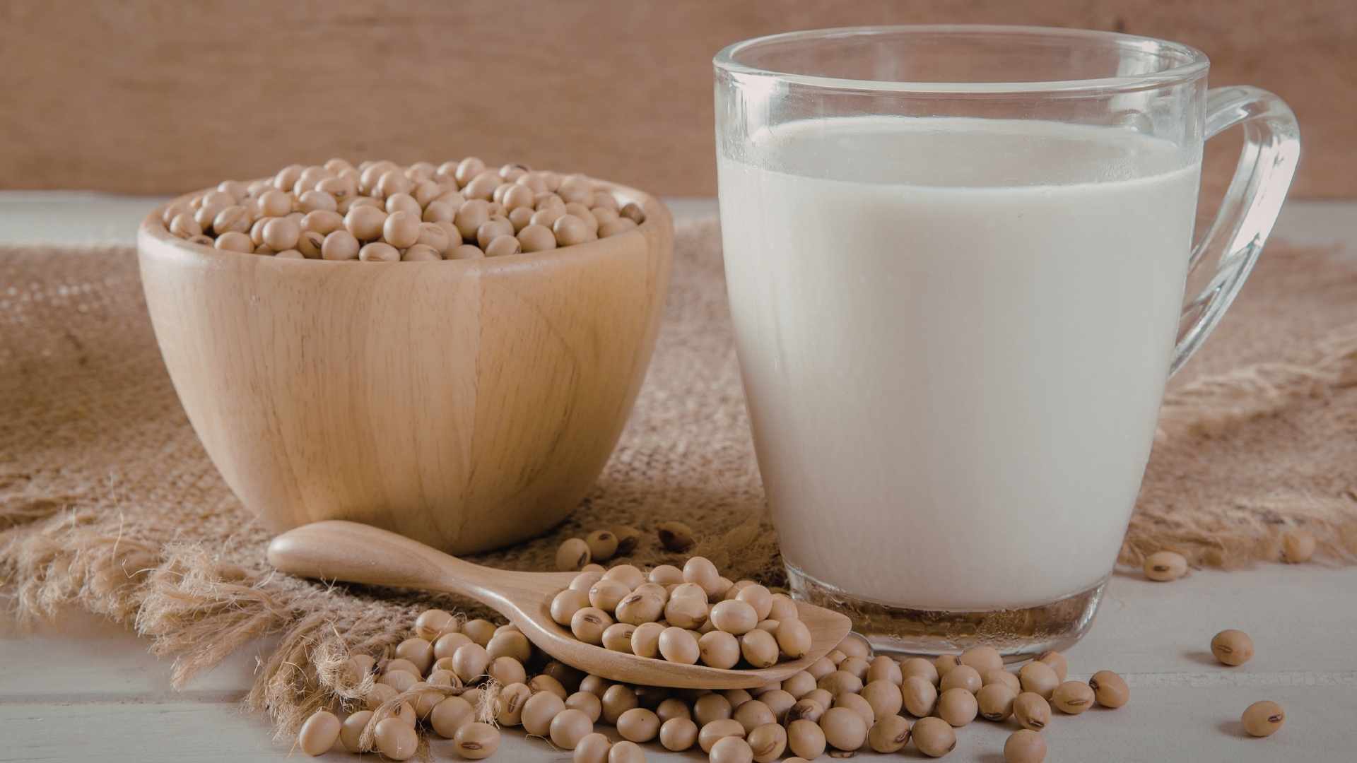 Dried soy beans next to a glass of soy milk